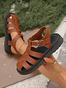 Nahaufnahme von braunen geflochtenen Gladiator-Sandalen mit dicker schwarzer Sohle.