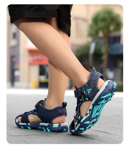 Detailed side view of boy wearing blue camouflage sporty sandals on outdoor pavement