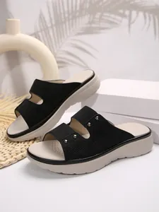 Detailed macro view of black platform slide sandals featuring metal studs and textures