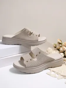 Detailed view of beige women's platform slides with gold studs and textured straps