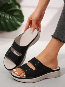 Detail view of women's black platform slides with stylish silver studs and thick sole.