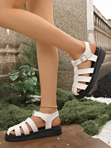 Seitenansicht weißer Fisherman-Sandalen mit dicker schwarzer Sohle im Freien Garten