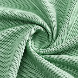 Gros plan sur la texture du tissu piqué en maille verte respirante pour polo homme.