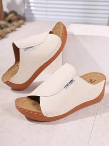 Close-up of cream women's wedge mules with open-toe design and comfy thick soles.