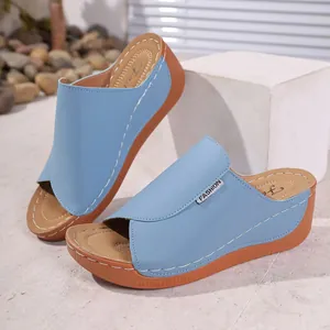 Detailed view of light blue wedge sandals featuring white stitching and fashion label
