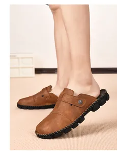 Close-up view of men's brown leather mule sandals with hand-stitched details on model feet