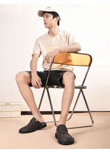 Detail view of brown hand-stitched men's casual mules worn by a model in casual setting.
