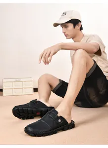 Detail of men's black hand-stitched backless loafers worn by a model in a casual setting