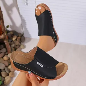 Close-up of comfortable black wedge slippers with white stitching and FASHION tag detail