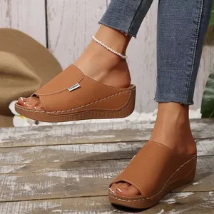 Detailed view of brown wedge heel slides for women featuring white decorative stitching