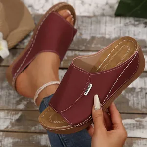 Detail view of comfortable burgundy wedge sandals featuring stylish white contrast stitching