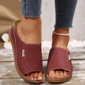 Close-up detail of women's burgundy wedge sandals with contrast stitching and tag