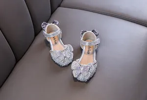 Gros plan sur les chaussures argentées pour filles avec un grand papillon strass