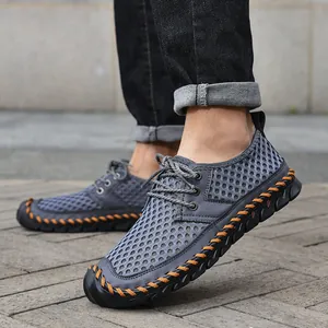 Men's breathable mesh water shoes with orange hand-stitched detailing on sidewalk.