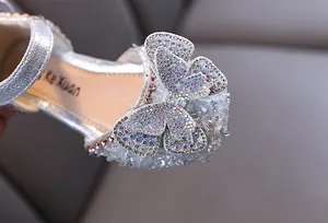 Vue macro d'un papillon en strass étincelant sur des chaussures de princesse pailletées.