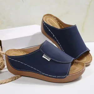 Detailed view of navy blue women's wedge slide sandals with white contrast stitching