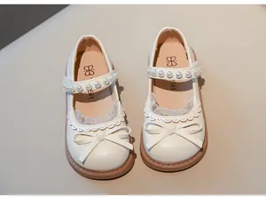 Vista detallada de zapatos de princesa Mary Jane para niñas con perlas y lazo en color crema