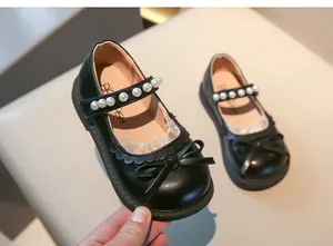 Vista detallada de zapatos Mary Jane de cuero negro para niña con perlas y un lazo.