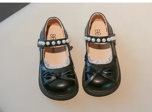 Detalle de zapatos Mary Jane negros para niña con perlas elegantes y lazo decorativo.