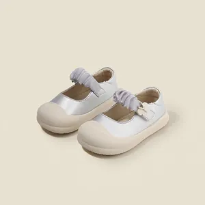 Vista detallada de zapatos de piel plateados para bebés con dije de mariposa
