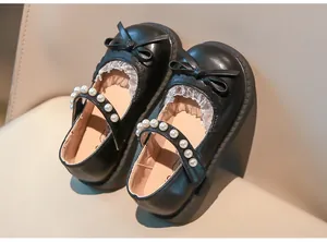 Primer plano de zapatos de princesa negros para niña con lazo de encaje y perlas