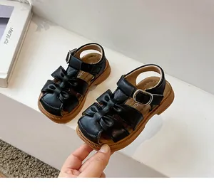 Close-up view of black toddler sandals featuring bow details and flexible soft rubber soles