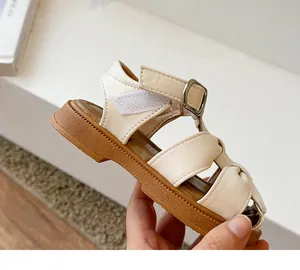 Close-up detail of beige girls' closed-toe sandal with velcro strap and textured sole