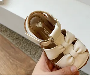Detailed view of white faux leather toddler girl sandals with bow accent and strap