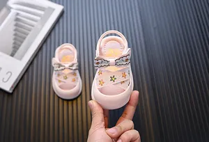 Detailweergave van roze peutersandalen met geborduurde bloemenstrik en zachte zool