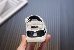 Close-up back detail of cream toddler lighting sandals featuring Bear print on the strap