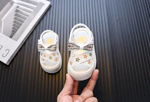 Detailopname van witte meisjessandalen met geborduurde bloemen en strikje voor baby's