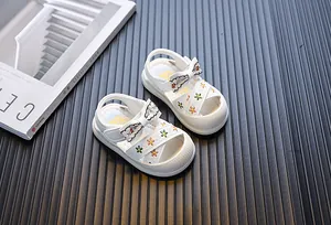 Gedetailleerde close-up van witte babysandalen voor meisjes met strik en borduurwerk