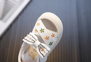 Detailopname van een witte meisjessandaal met bloemenborduurwerk en een schattige strik