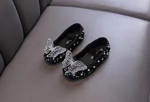 Primo piano di scarpe da principessa nere con farfalla di strass per bambina.
