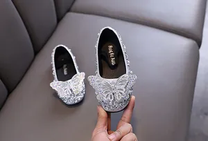 Primo piano di scarpe da principessa argento scintillanti per bambine con farfalla grande.