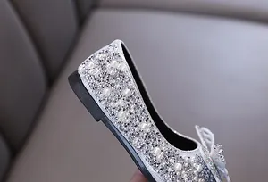 Dettaglio di scarpe da principessa per bambina con strass argentati e perle luccicanti