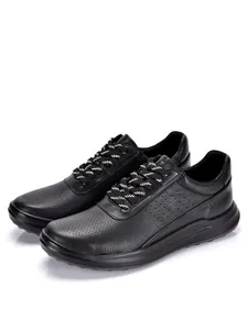 Detalle de zapatillas de cuero negro con perforaciones transpirables y suelas suaves