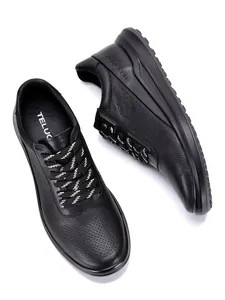 Primer plano de zapatillas de cuero negro para hombre con detalle perforado transpirable.