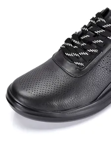 Primer plano detallado de zapatillas de cuero negro con punta perforada y cordones