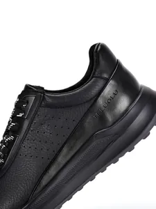Primer plano de zapato de cuero negro con logo TELUOLU y laterales perforados para hombre