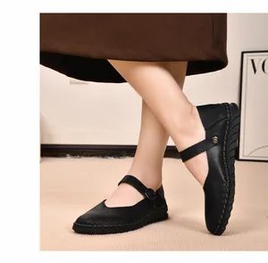Detailaufnahme schwarzer Mary-Jane-Flachschuhe mit Schnallenriemen am Fuß eines Models.
