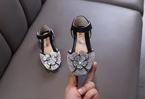 Detailopname van de schitterende strass bloem op deze zwarte prinsessenschoen voor kleine meisjes