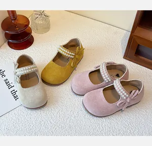 Detalle de zapatos Mary Jane de gamuza para niñas con elegantes correas de perlas y lazos.