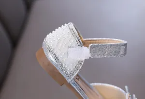 Detailweergave van elegante zilveren prinsessenschoenen voor meisjes met parels en glitter.