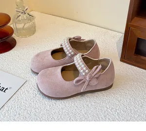 Primer plano de merceditas de ante rosa para niña con perlas y lazo lateral.