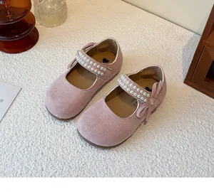 Detalle de zapatos de princesa en ante rosa con correas de perlas y adorno de lazo