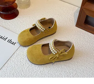 Vista detallada de zapatos de princesa amarillo mostaza para niña con perlas y un lazo.