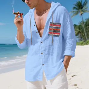 Men's blue linen hooded shirt with bohemian pocket detail in a sunny beach setting