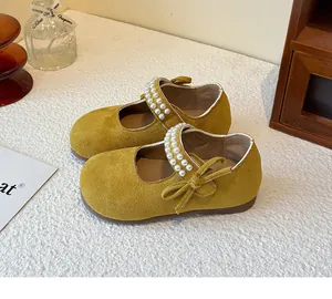 Primer plano de merceditas de ante amarillo para niña con tiras de perlas y un lazo