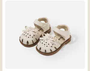 Close-up view of beige toddler girl sandals featuring bow decoration and floral cutouts